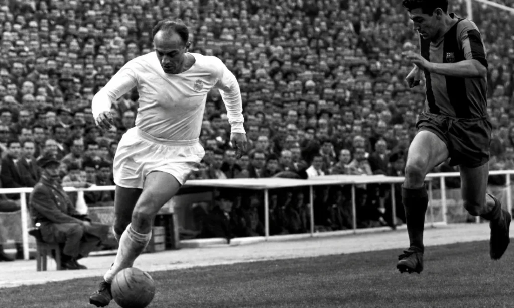 Vintage football action image for an Alfredo Di Stefano article showing a white-shirted forward driving with the ball