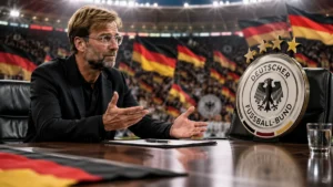 Jürgen Klopp seated at a table facing a large Germany football crest, with German flags and supporters in the background.